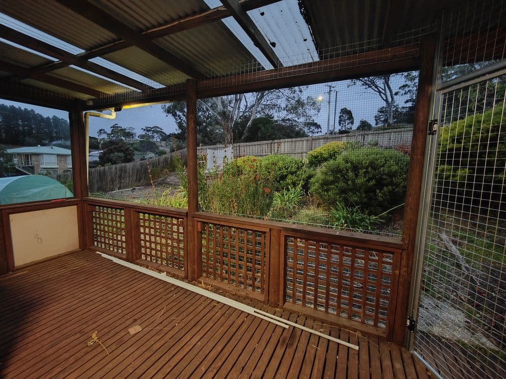 A timber deck enclosed with mesh and lattice panels, looking out over the garden